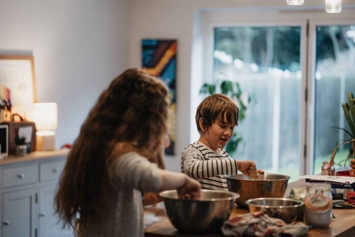 Two young children stirring mixing bowls