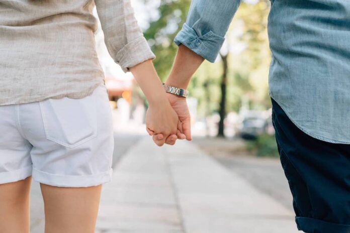 Couple holding hands while walking on street