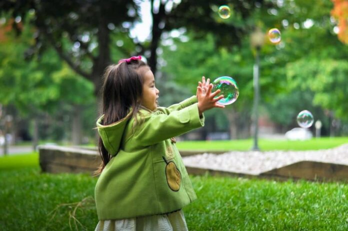 Child playing with bubbles at a park