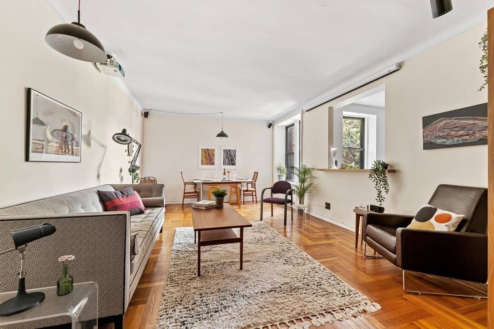 Furnished living room with couch, coffee table, rug, and kitchen table in background