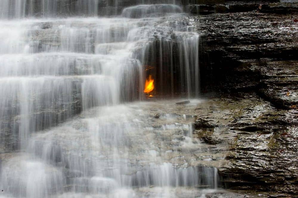 Eternal flame within a grotto of a waterfall