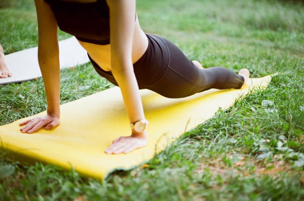 Woman stretching on yoga mat on grass